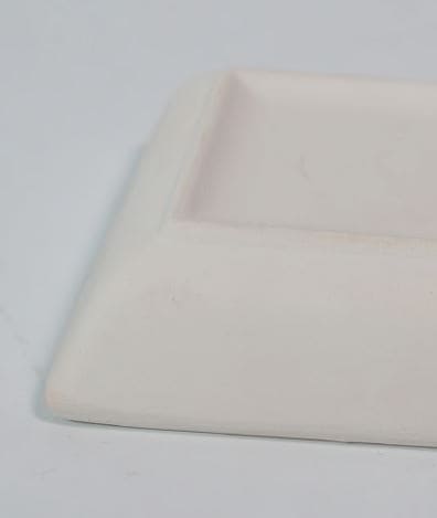 Detalle del borde biselado y acabado mate del plato de pan de cerámica artesanal.